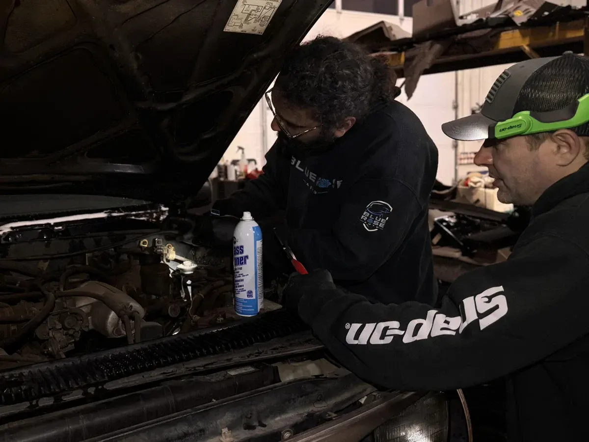Two technicians working under the hood of a truck