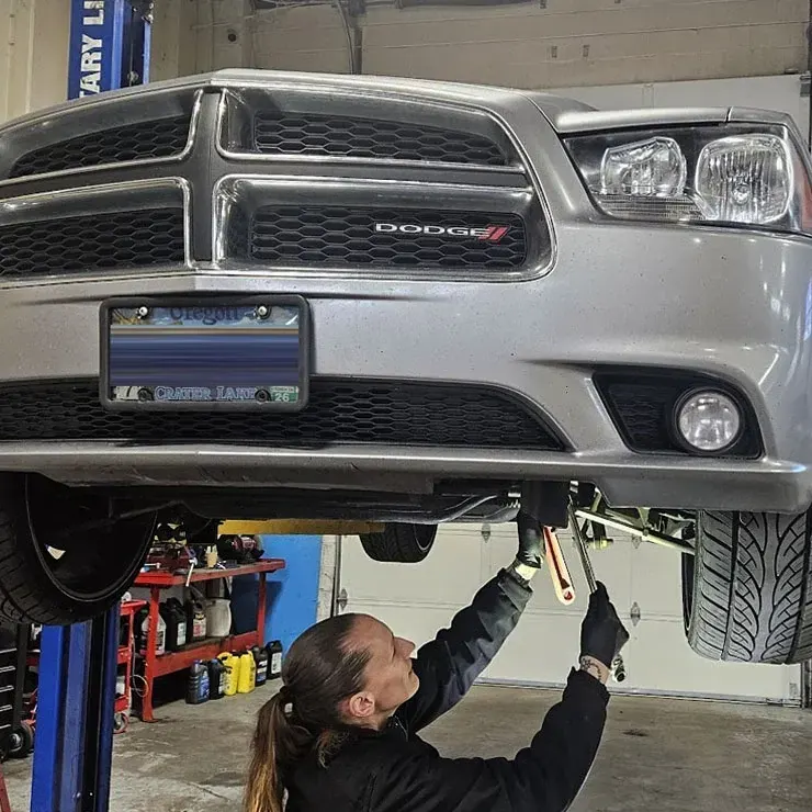 Technician working under a Dodge Charger on the lift